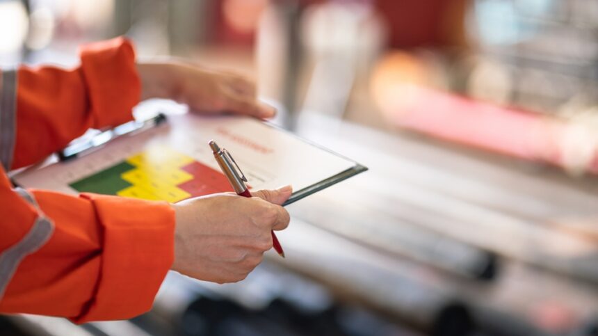 a-factory-worker-holding-luxury-pen-and-paper-form-for-risk-assessment